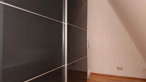 Une pièce avec une porte coulissante sombre, un plancher en bois et un mur blanc.