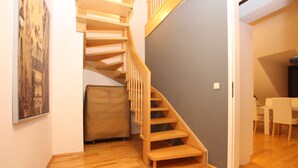 Un escalier en bois menant à un deuxième étage, un espace couvert et un coin repas avec des chaises et une table.