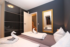 A hotel room with a large mirror, a wardrobe, and two beds with white towels shaped like swans. - SLADKIY SLIVA Boutique Apartment (Leipzig)