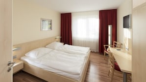 A hotel room with a double bed, a desk, a chair, a TV, and a window with curtains. - Autohof & Hotel Salzbergen (Salzbergen)