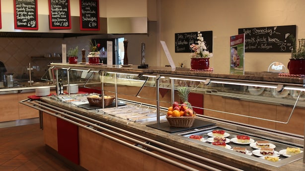 A buffet counter with various food items and a selection of fruits. - Autohof & Hotel Salzbergen (Salzbergen)