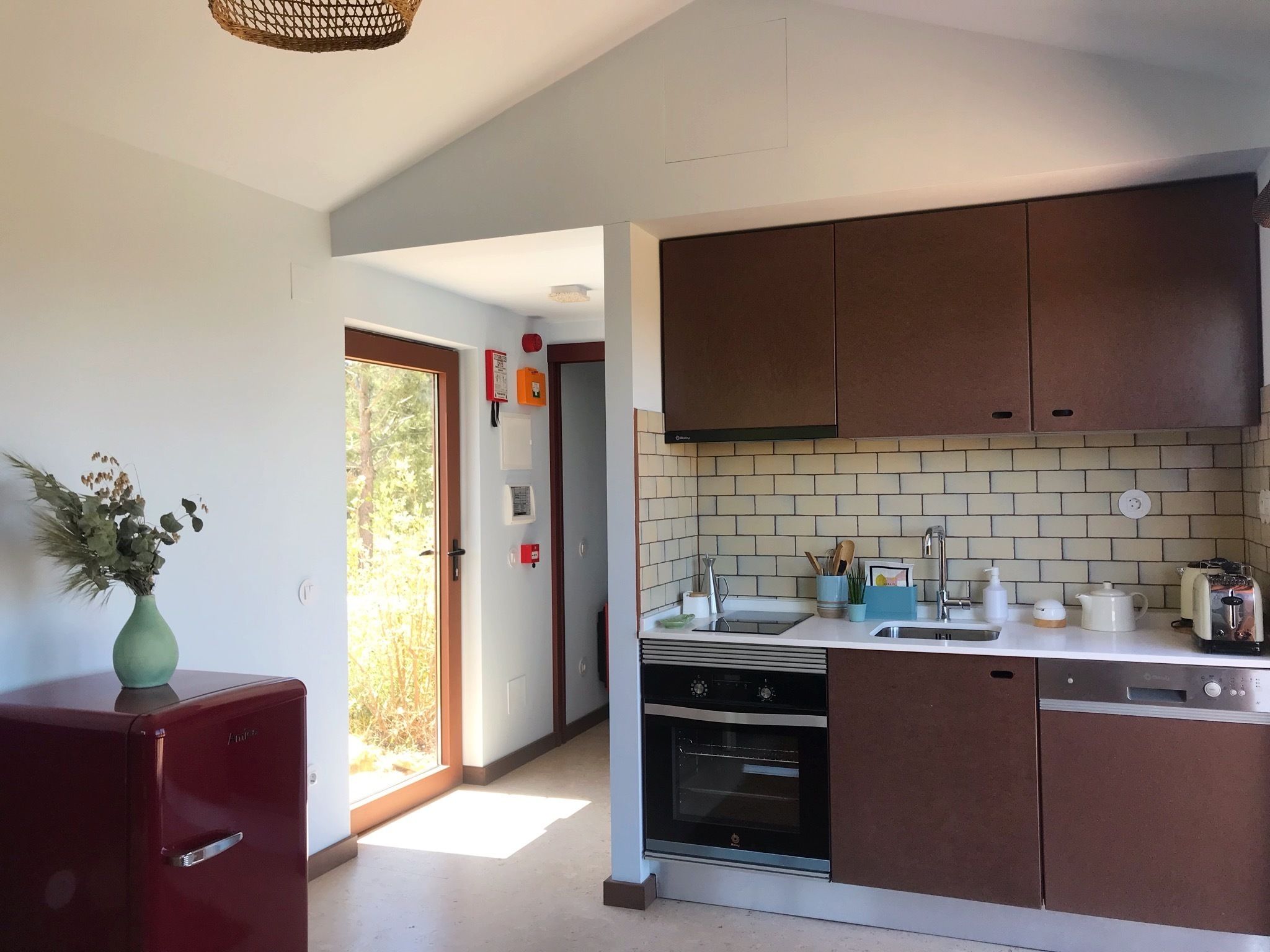 A modern kitchen with brown cabinets, a built-in oven, and a dishwasher.