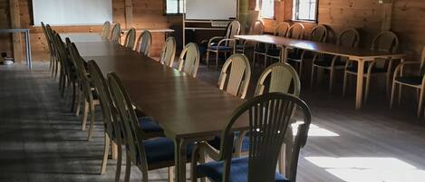 Un salón de conferencias con una larga mesa y sillas, paredes de madera y una pizarra.