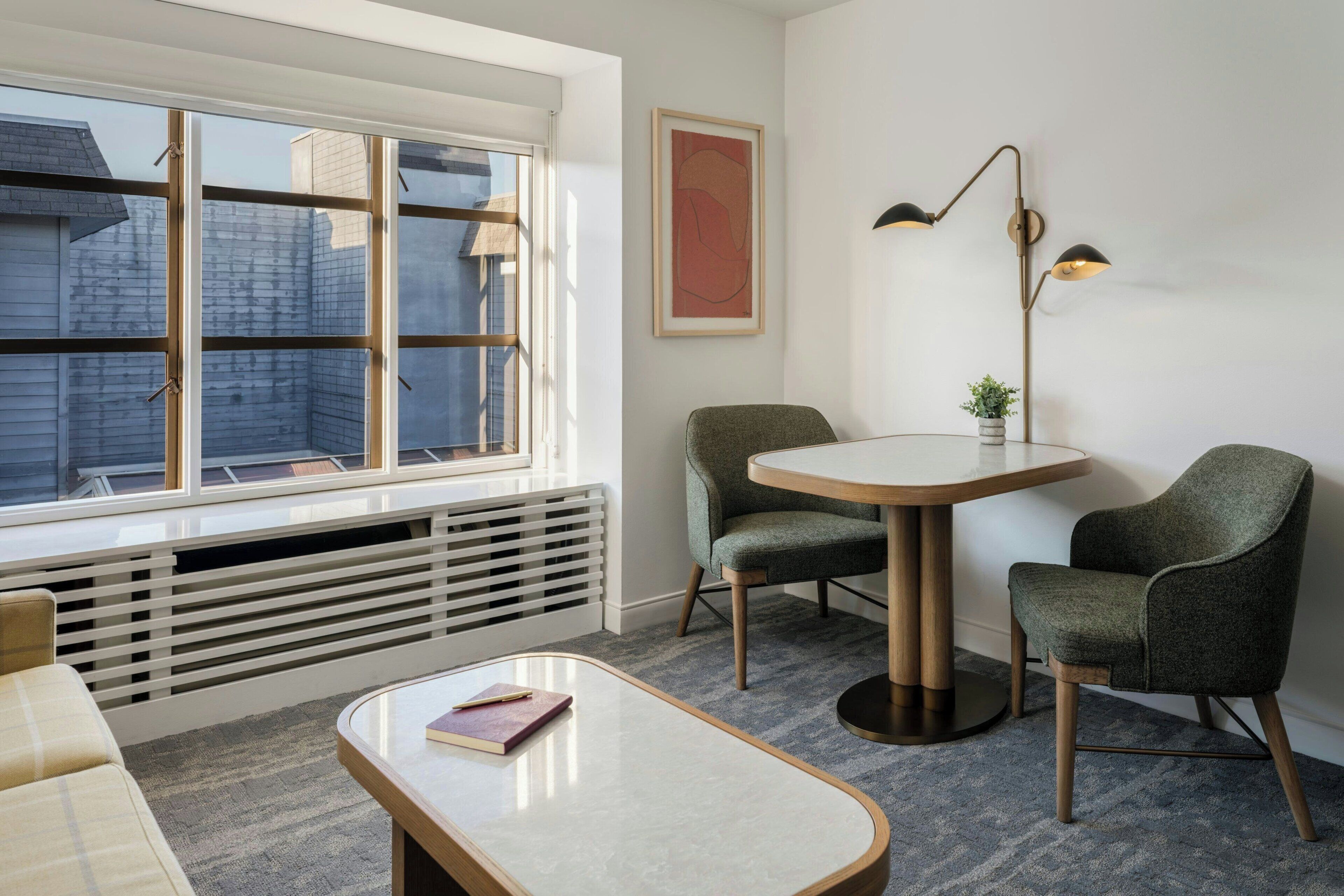 Een moderne kamer met een groot raam, een ronde tafel, twee stoelen, een vloerlamp en een radiator.