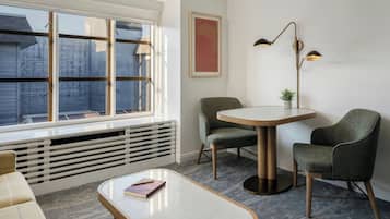 Ein modernes Zimmer mit großem Fenster, einem runden Tisch, zwei Stühlen, einer Stehlampe und einer Heizung.