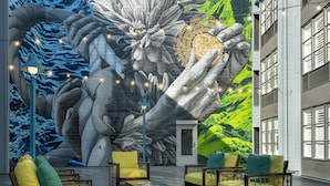 A mural with hands holding a globe, outdoor seating with cushions, and a building facade with windows. - Marriott Vacation Club®, San Francisco (San Francisco)