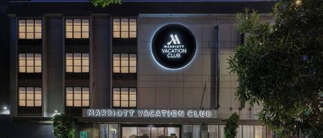 A Marriott Vacation Club building with a prominent illuminated sign, large windows, and a well-lit entrance.
