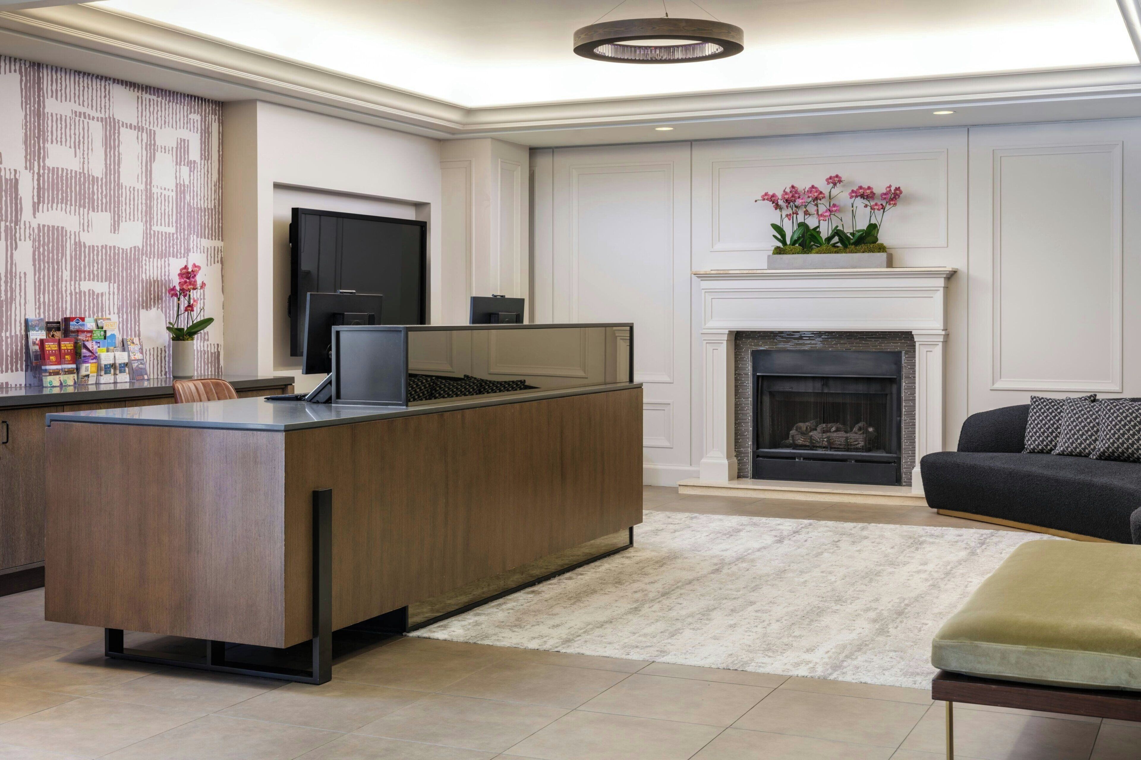 A modern living room with a wooden entertainment center, a fireplace, and a TV mounted on the wall.