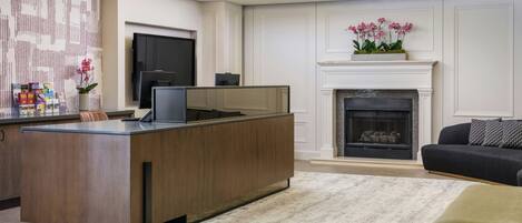 A modern living room with a wooden entertainment center, a fireplace, and a TV mounted on the wall.