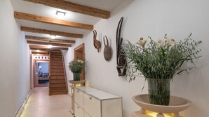 Ein Flur mit Holzbalken, einer Treppe, einem Schrank und einer Vase mit Blumen.