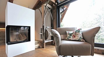 Quarto moderno com lareira, uma poltrona de couro com almofada estampada e piso de madeira.