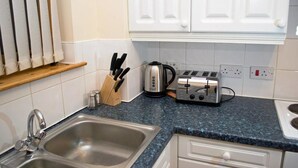 A kitchen with a double sink, a toaster, a kettle, and a knife block.