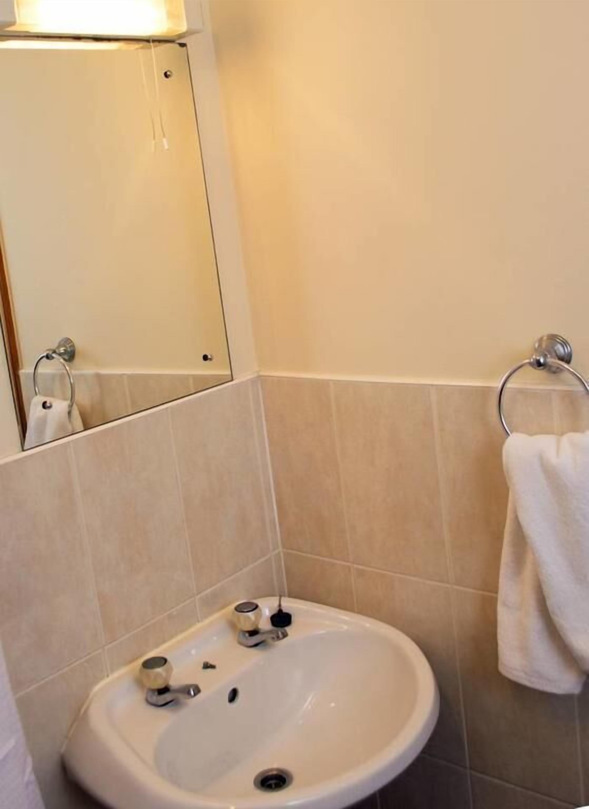 A bathroom with a white sink, a mirror, and a towel rack.