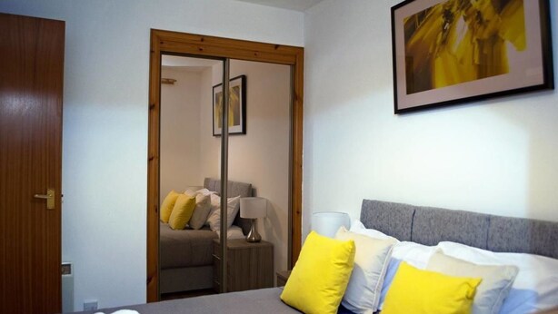 A hotel room with a bed, a wardrobe, a mirror, and a framed picture on the wall.