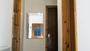 A narrow hallway with wooden doors and a small window.
