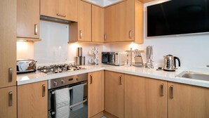 Eine moderne Küche mit Holzausbau, Edelstahlgeräten und einem großen Flachbildfernseher, der über der Arbeitsplatte angebracht ist.