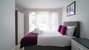 Ein Schlafzimmer mit einem Bett, einem Nachttisch, einem Kleiderschrank und einem Fenster mit Jalousien.