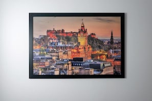 A framed cityscape with a prominent castle-like structure on a hill, surrounded by buildings.