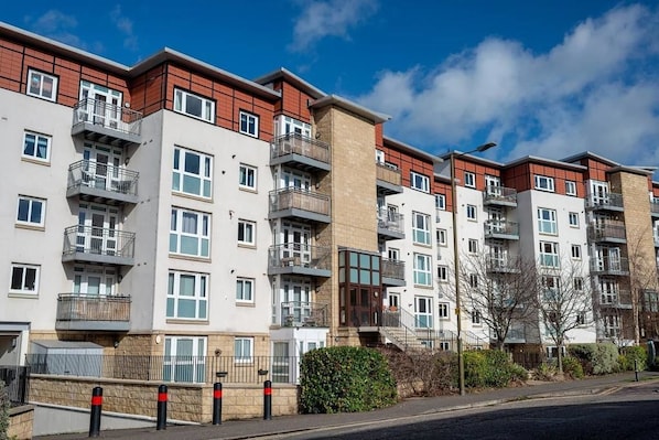 A row of modern multi-story residential buildings with balconies, large windows, and a clear sky.