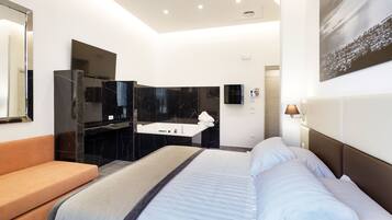 Ein modernes Hotelzimmer mit einem großen Bett, einer Couch, einem Badezimmer mit Spiegel und einem Bild an der Wand.