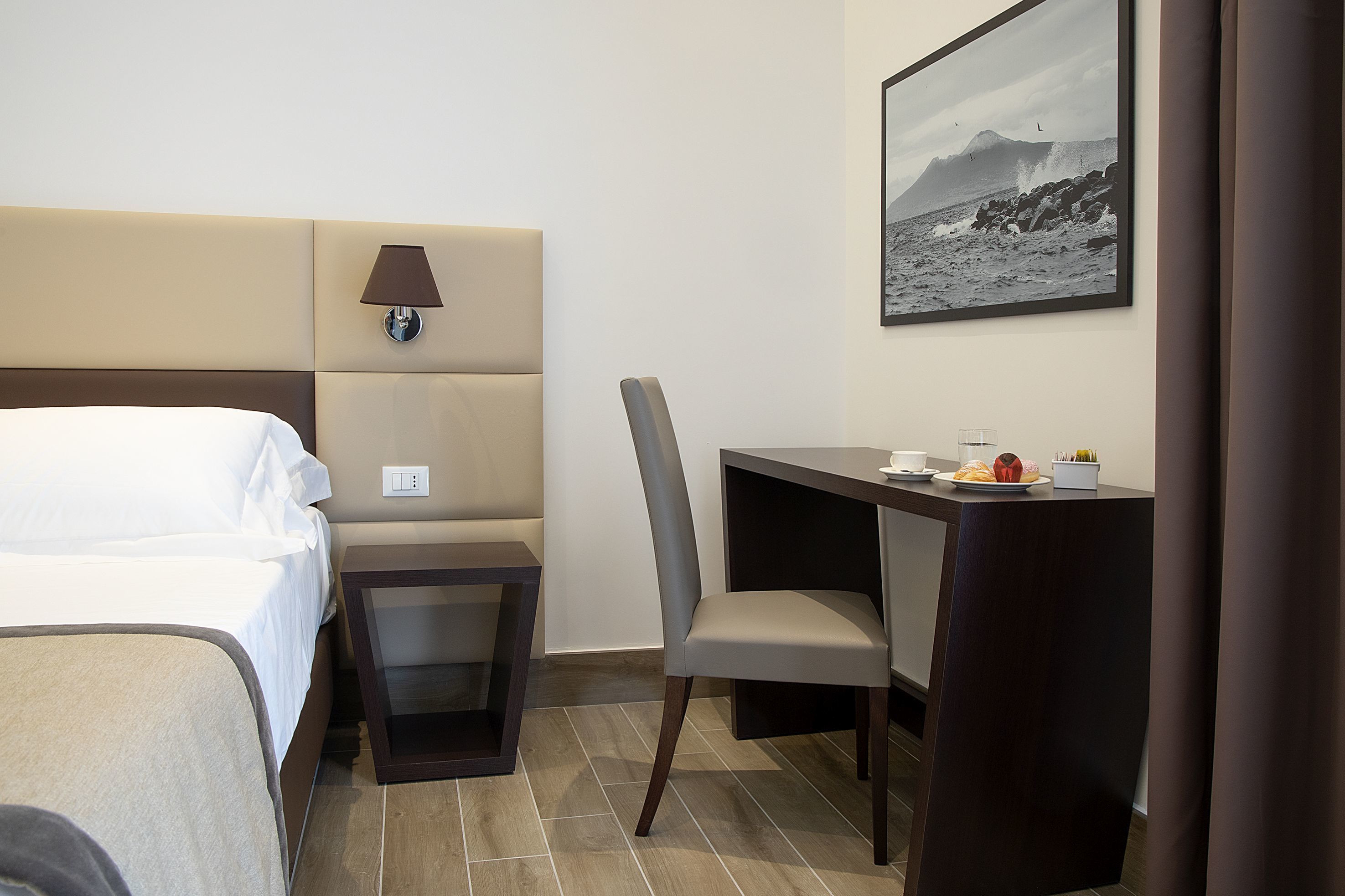 Una habitación de hotel con cama, escritorio, silla y lámpara.