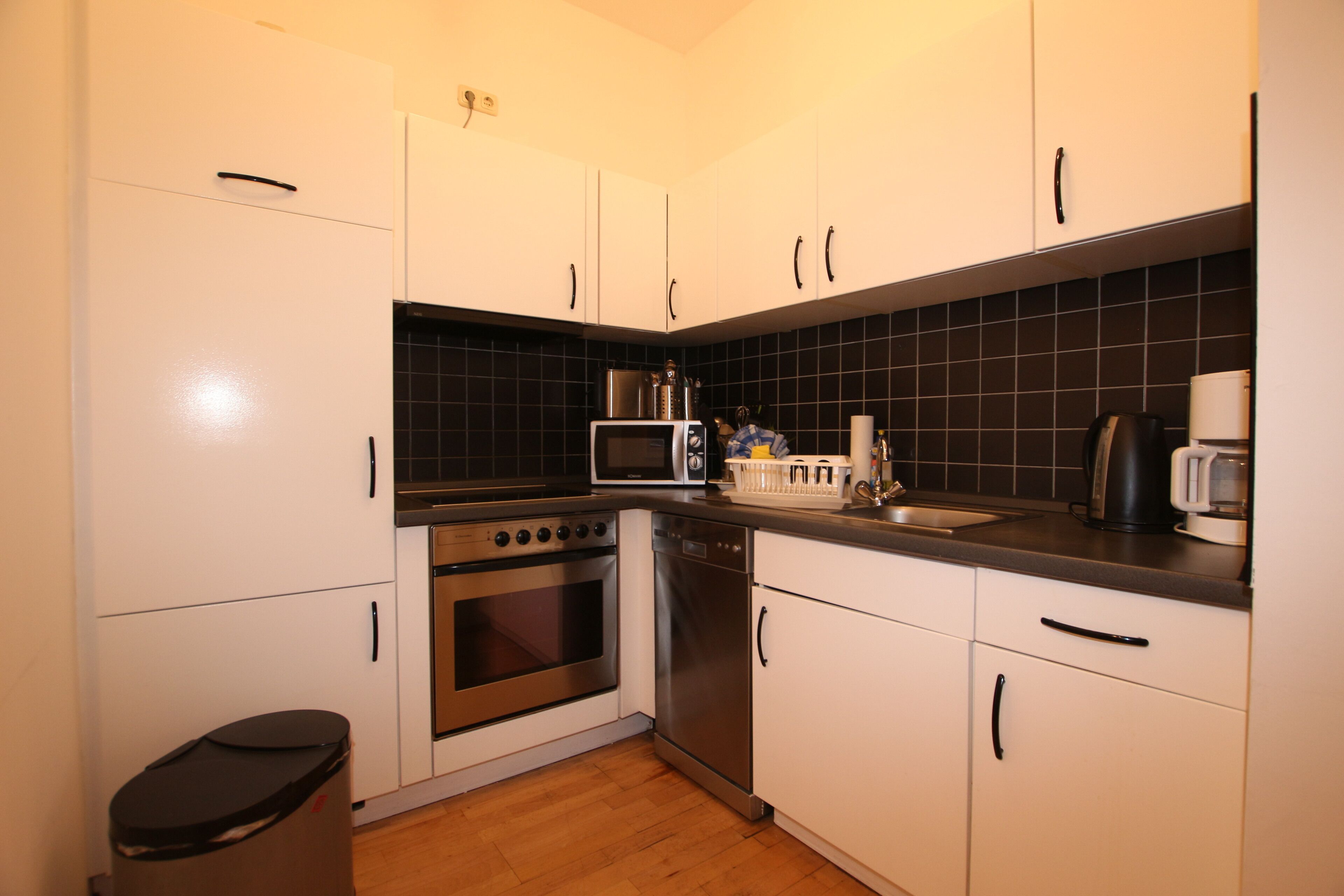 A compact kitchen with white cabinets, a microwave, a stove, and a dishwasher.