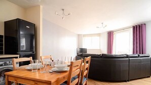 A modern living space with a dining area, a black refrigerator, a black TV, and a black sofa. - Wonderful Apartment nr Central Edinburgh (Edinburgh)