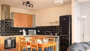 A modern kitchen with black and white tiled backsplash, wooden cabinets, and a dining area with a table and chairs. - Wonderful Apartment nr Central Edinburgh (Edinburgh)