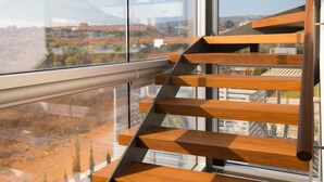 A modern interior with a wooden staircase leading to a balcony. - Cove Seaview Villas (Ayia Napa)