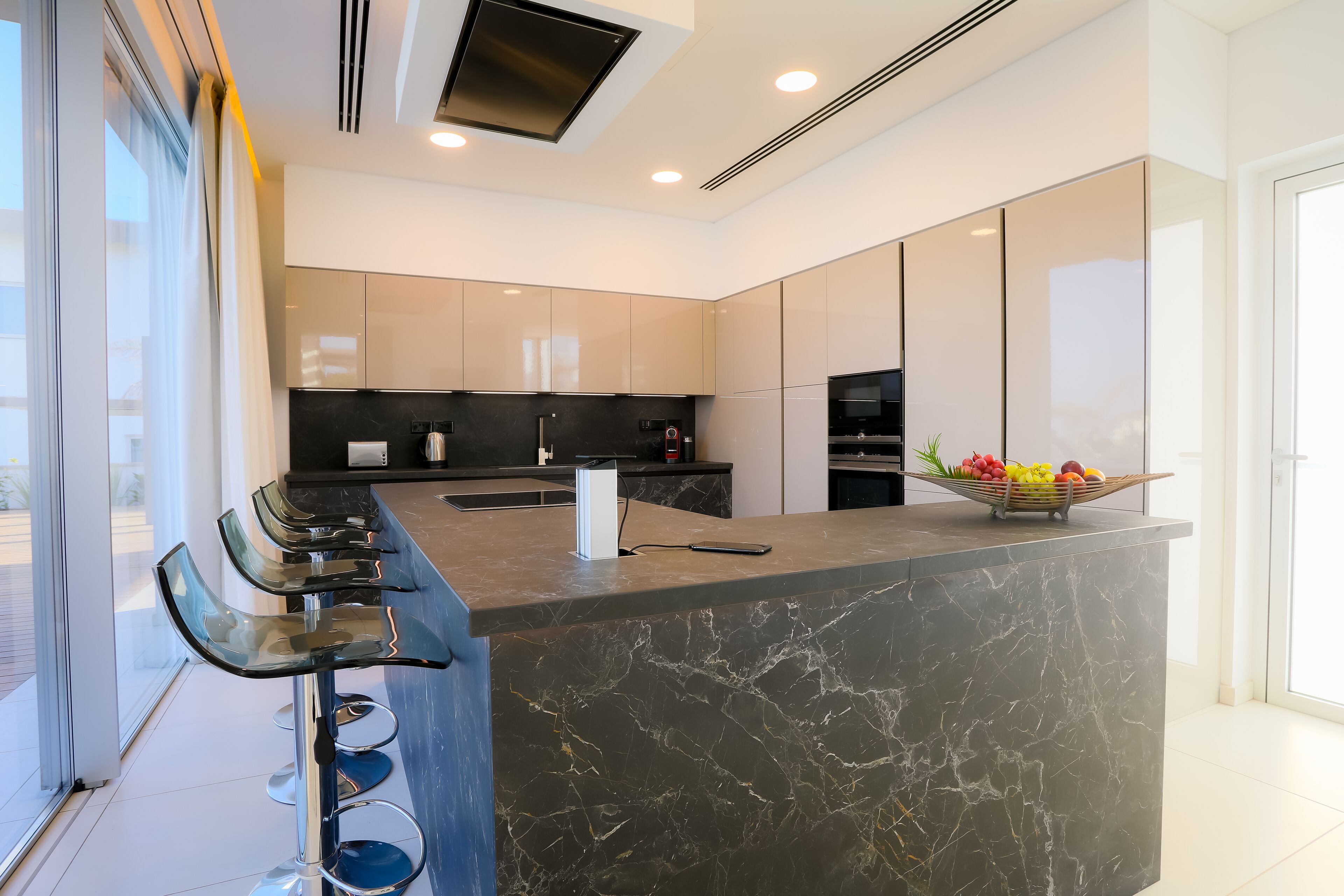 A modern kitchen with a marble island, stainless steel appliances, and a fruit bowl.