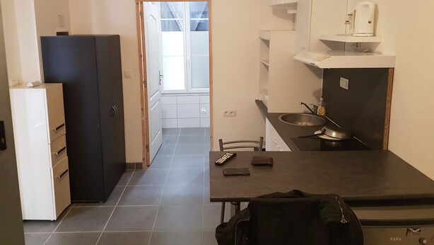 A compact kitchen with a refrigerator, stove, and a small dining area. - new studio - TARBES (Tarbes)