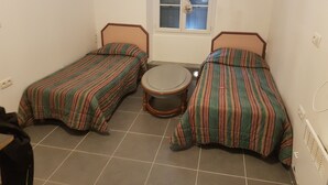 A small room with two single beds, a round table, and a window with curtains. - new studio - TARBES (Tarbes)
