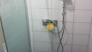 A shower with a handheld showerhead, a wall-mounted faucet, and a yellow bath sponge. - new studio - TARBES (Tarbes)