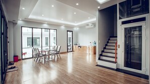 A spacious living area with a wooden floor, a dining table with chairs, a kitchen area, and a staircase leading to an upper level. - The Oriental Ruby (Dong Hoi)