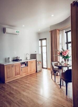 A modern kitchen with wooden cabinets, a refrigerator, and a sink. There is a dining area with a table and chairs.