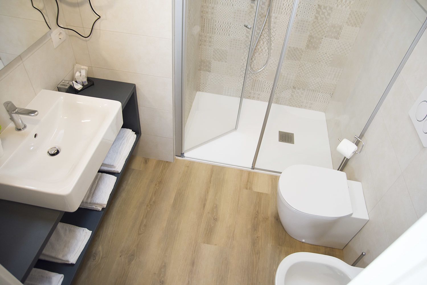 A modern bathroom with a white sink, toilet, and shower.