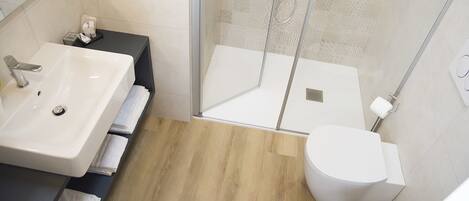 A modern bathroom with a white sink, toilet, and shower.