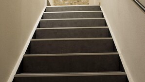A staircase with a stone wall at the top, a metal handrail on the right, and a plain wall on the left. - Casa Beccherie (Lazise)