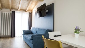 A modern living room with a blue sofa, a white table, and a yellow chair. - Casa Beccherie (Lazise)