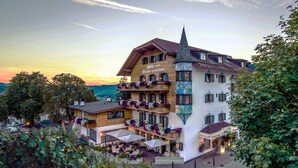 A hotel with a traditional Alpine architectural style, featuring a prominent tower and multiple balconies with flower boxes. - Enzian Genziana (Castelrotto)