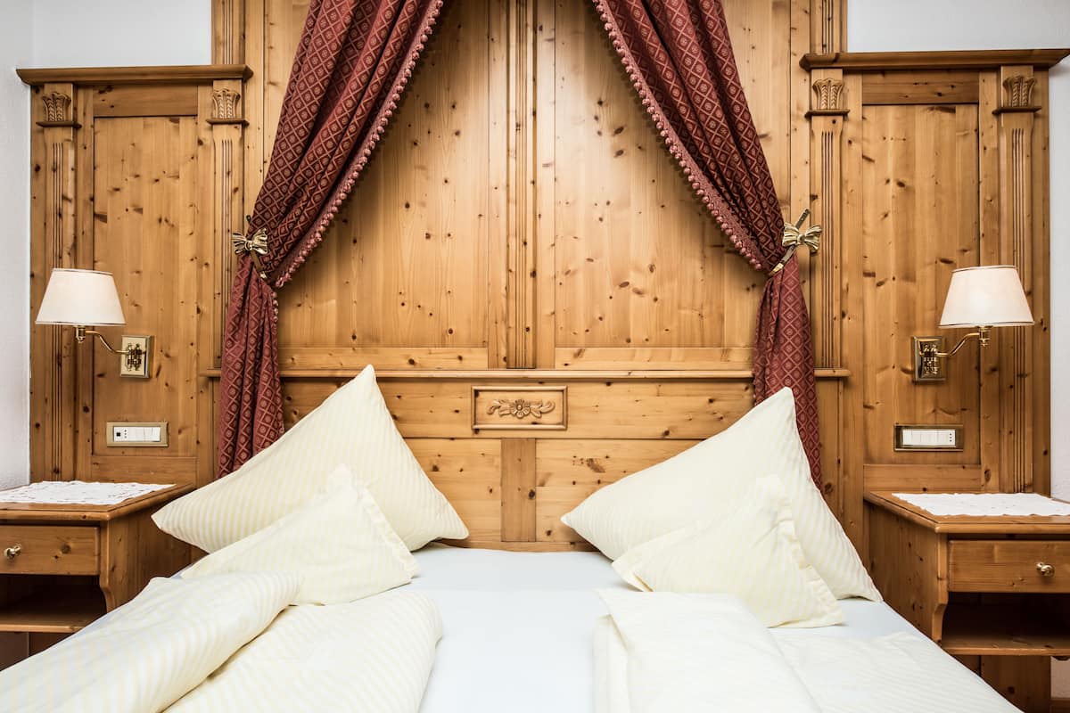 A wooden bedroom with a large bed, two bedside tables, and a nightstand.