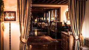 A warmly lit hallway with striped curtains, a patterned rug, and a wooden cabinet with drawers. - Enzian Genziana (Castelrotto)