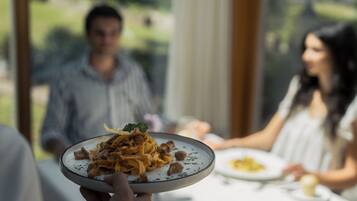 Una persona sostiene un plato de comida en un comedor con vistas a un jardín.