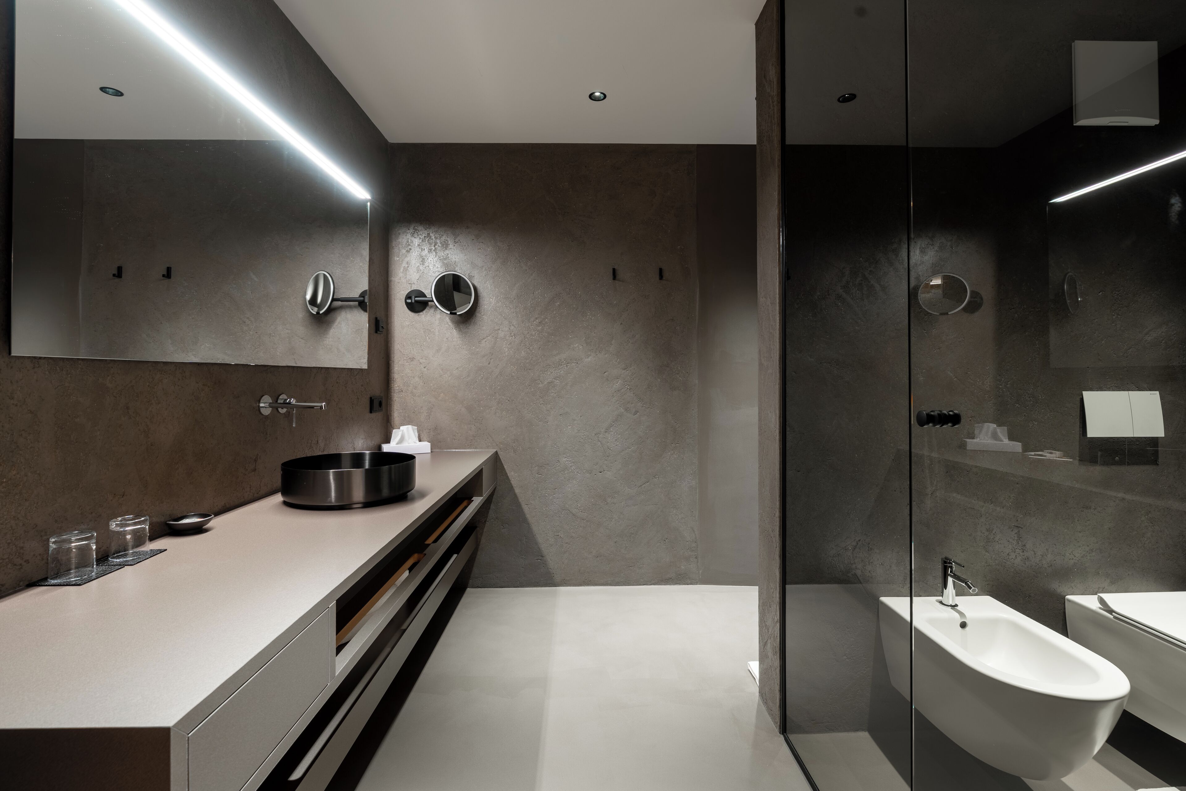 Un baño moderno con un espejo grande, un tocador con lavabo y una cabina de ducha de vidrio.