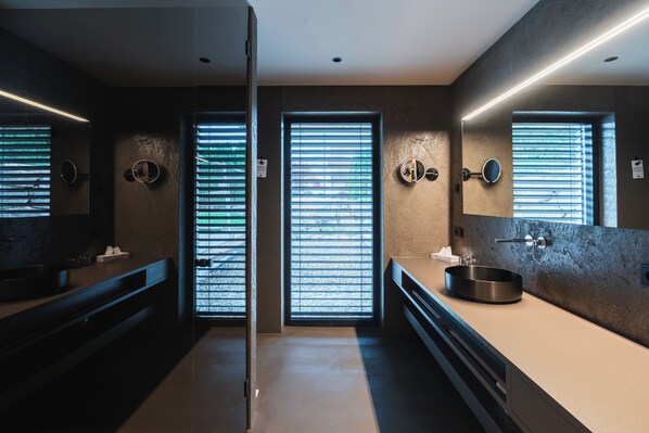 Un baño moderno con dos lavabos, un espejo grande y una ventana con persianas.