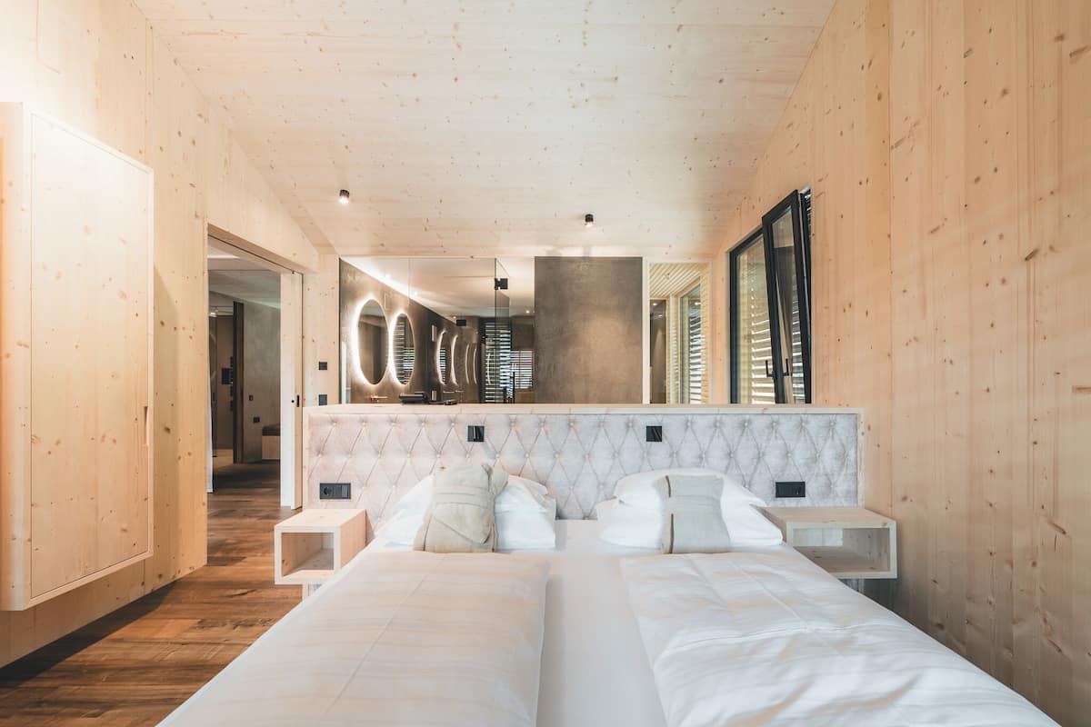 A modern bedroom with a large bed, two bedside tables, a marble headboard, and a large mirror.