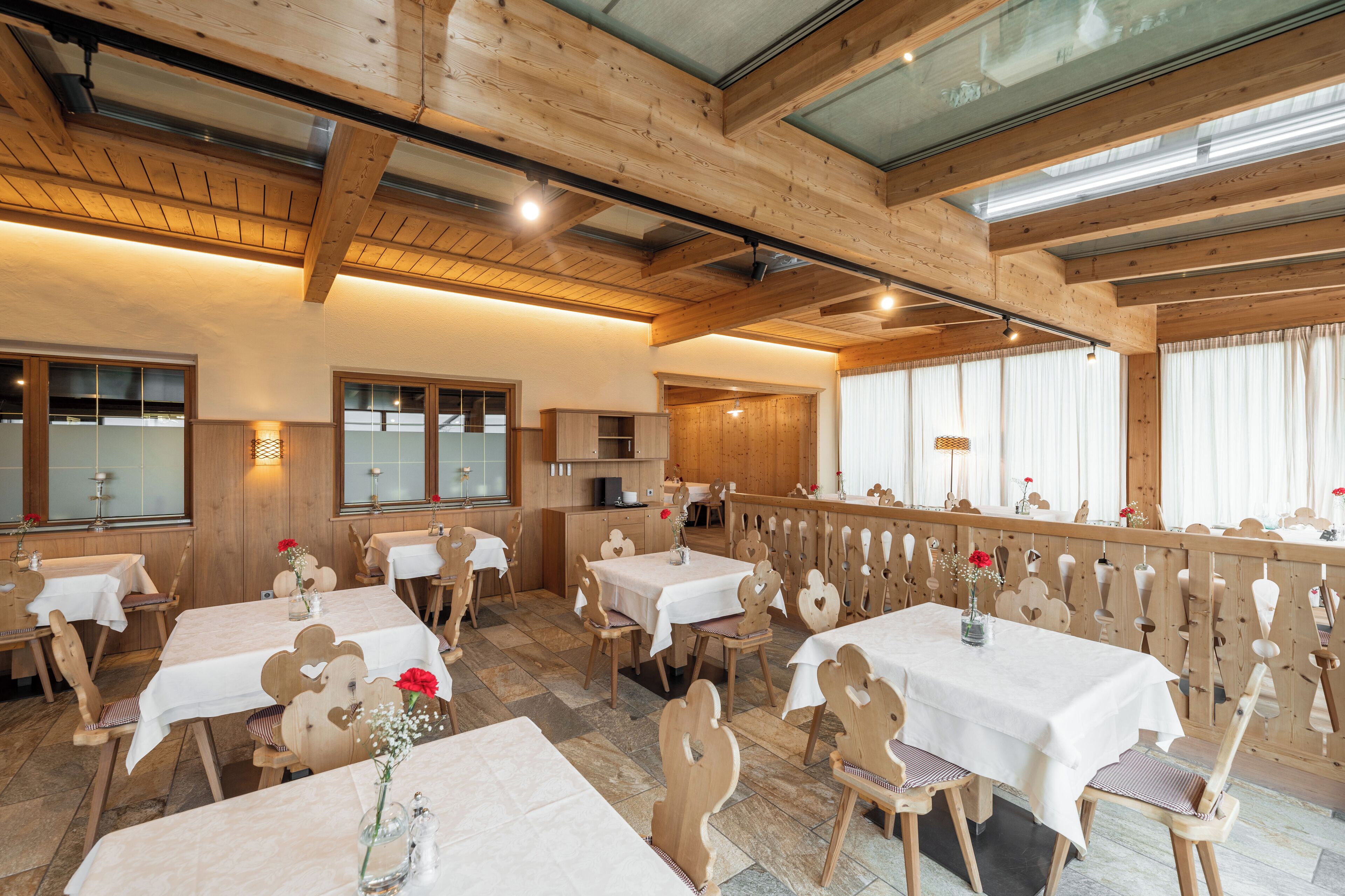 Un restaurante con interiores de madera, varias mesas y sillas.