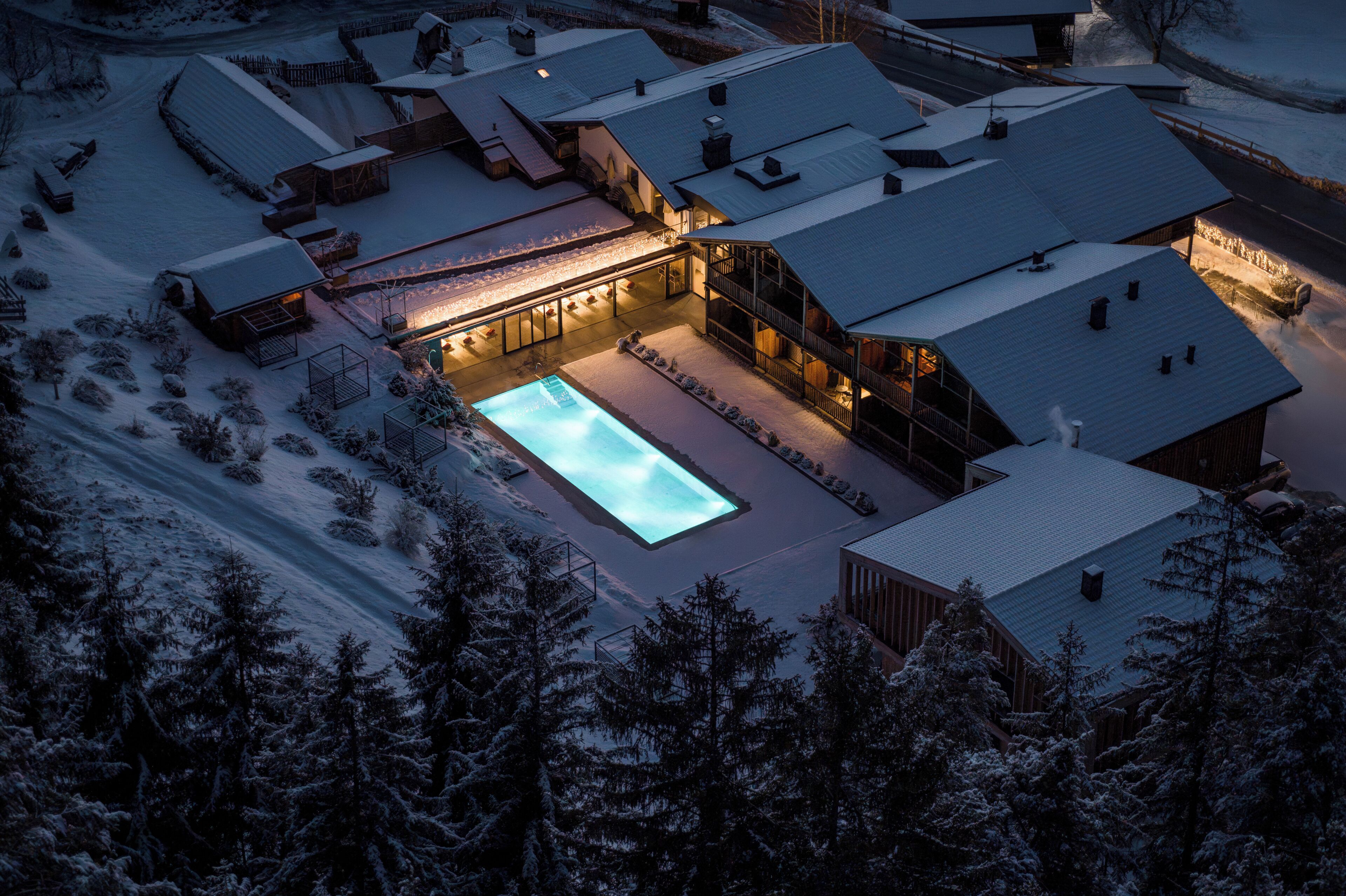 Une propriété enneigée dotée d’une piscine, de plusieurs bâtiments et entourée d’arbres.