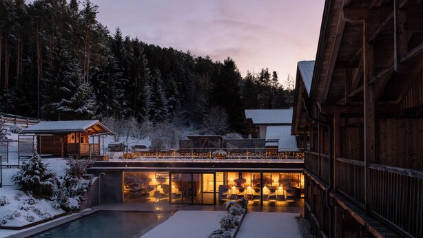 A wooden lodge with a pool and snow-covered landscape.