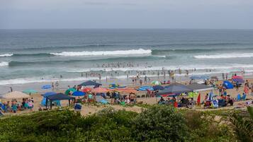 A beach with umbrellas, tents, and people.